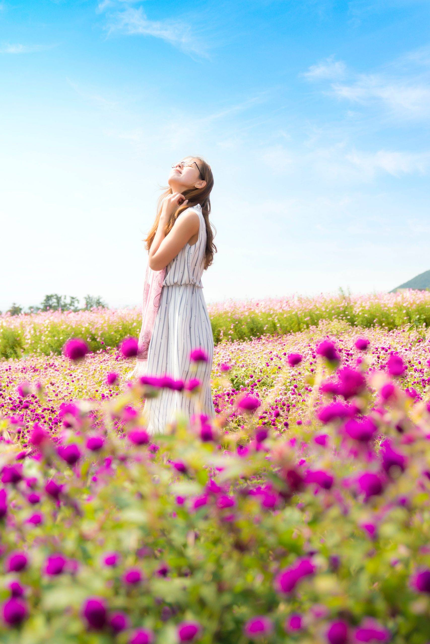 woman-standing-in-field-pink-flowers-white-dress